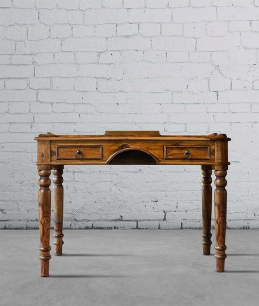 A solid wood study table with a rectangular top and a brass-handled drawer, set against a brick wall background.