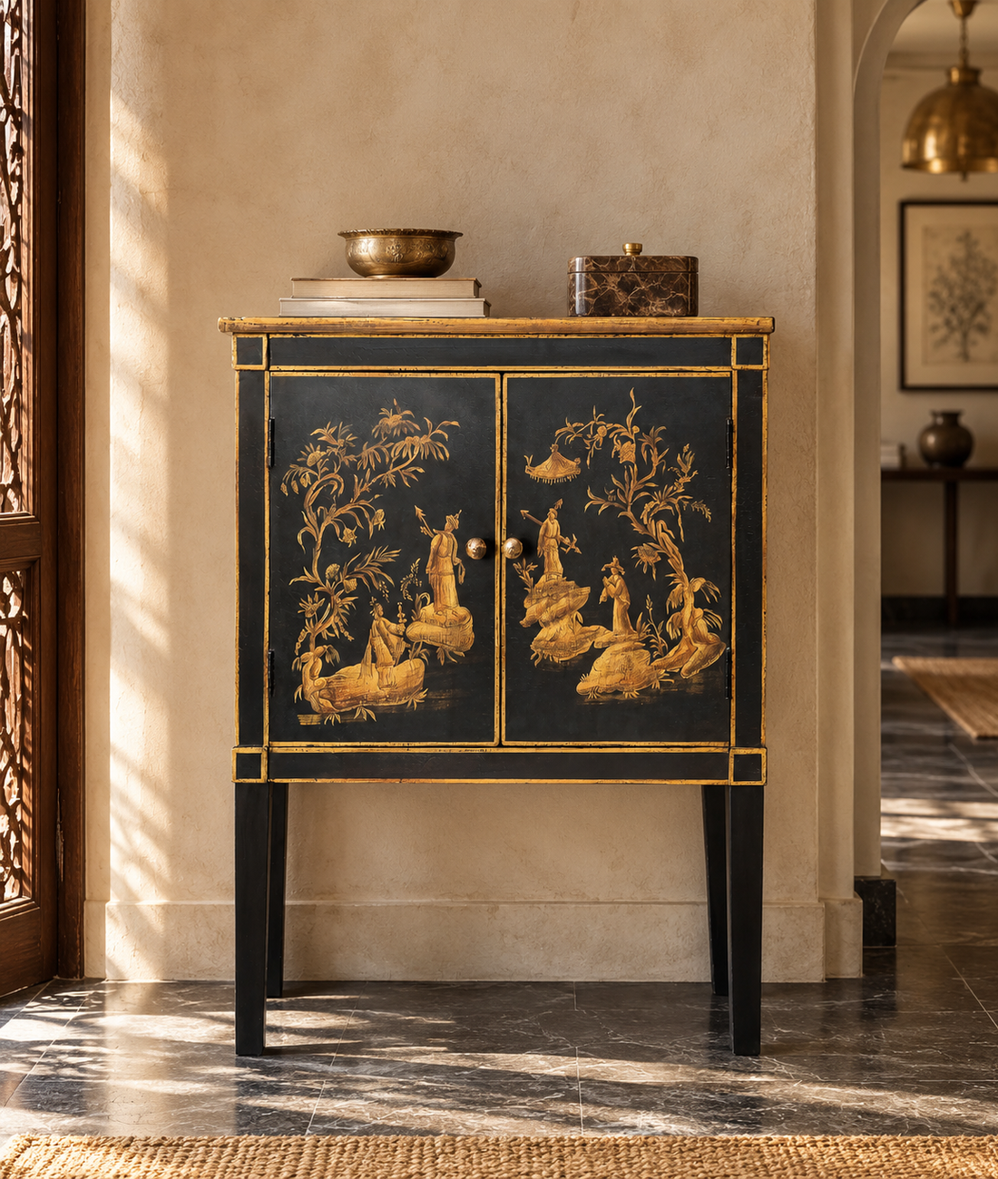 A black and gold Chinese-style cabinet with hand-painted figures and foliage, styled in a warm, sunlit interior hallway.